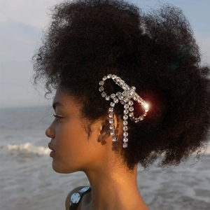 Detail view of shimmering rhinestone butterfly hair clip with tassels on a female model