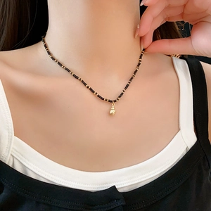 Detail shot of bohemian shell pendant necklace with black and gold seed beads on a model