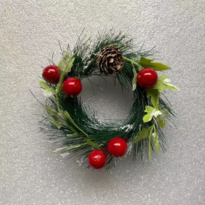 Detailed view of mini Christmas wreath with pine needles, red berries, and frosted pine cones