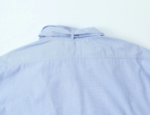Detail of light blue shirt back yoke showing high-quality stitching and cotton fabric