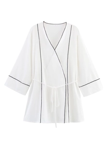Détail d'un haut kimono blanc avec bordure noire, taille nouée et texture de tissu doux