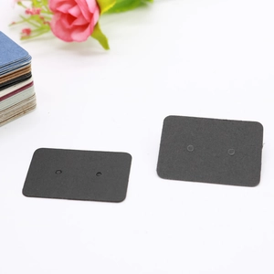 Close-up of black rectangular earring display cards with pre-punched holes on white backdrop
