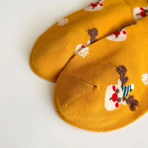 Detail of yellow Christmas socks featuring reindeer and snowflake knit patterns