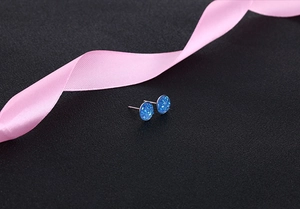Detail of round bright blue crystal cluster studs on black background with pink silk ribbon