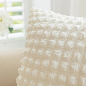 White cream puff bubble textured decorative throw pillow on a cozy home sofa background