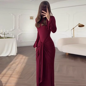 Détail d'une robe bordeaux à manches longues avec nœud à la taille et drapé élégant