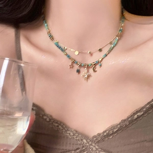 Close-up of double-layered star and moon necklace with turquoise beads and golden sequins