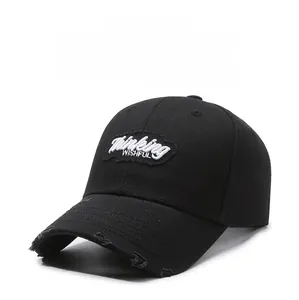 Close-up of black cotton baseball cap with distressed brim and embroidered patch detail