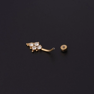 Close-up of curved gold belly ring bar with clear zircon stones and metal beads detail