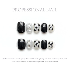 Detail of handmade press-on nails featuring black, silver glitter, and cow print patterns