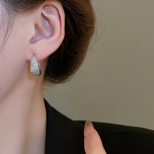 Close-up of silver U-shaped earrings with micro-paved zircons worn on model ear