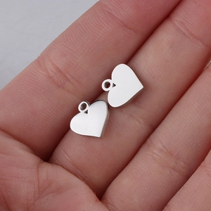 Macro shot of two silver heart-shaped stainless steel pendants on a person's palm