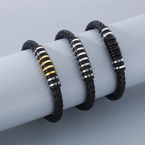 Detail of woven black leather bracelets with gold, silver, and black metal rings