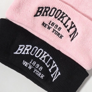 Detailed close-up of Brooklyn New York embroidery on ribbed knit beanies in pink and black