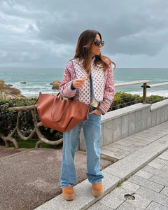 Detail of pink floral quilted jacket and brown leather tote bag in an outdoor setting