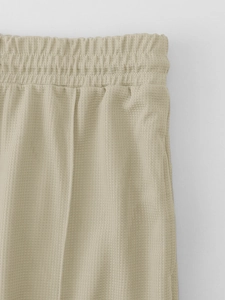 Close-up of elastic waistband and waffle texture fabric on beige leisure trousers