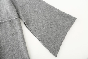 Dettaglio di cappotto in maglia grigia con maniche ampie e texture a coste fini