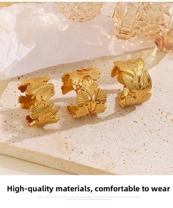 Detailed close-up of 18K gold leaf-shaped jewelry with realistic textures and brushed metal