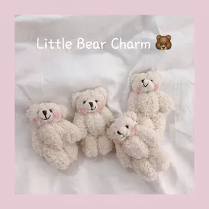Four white plush bear charms with curly fur and embroidery for bags or keychains