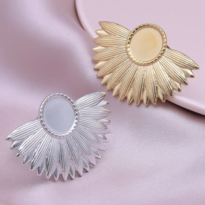 Macro shot of gold and silver radial fan-shaped metal brooches on purple silk fabric