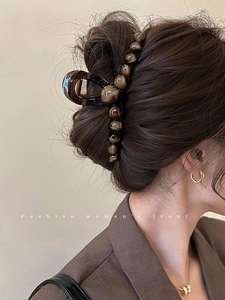 Dettaglio della pinza per capelli con perline sfumate marrone scuro indossata da donna