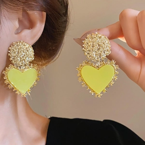 Detail of vintage gold textured earrings with large yellow resin heart pendants