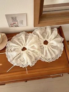 Close-up of beige lace scrunchies with delicate ribbon bows and pearl bead accents