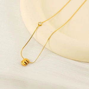 Minimalist gold bubble letter M necklace with sparkling zircon accent on a fine chain