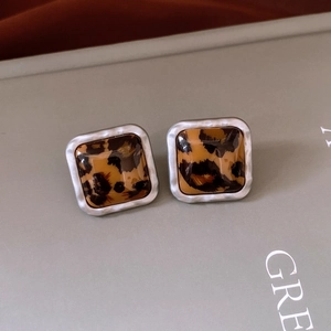 Détail macro de boucles d'oreilles carrées en résine léopard avec bord en métal argenté