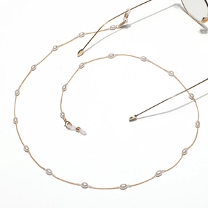 Detail of elegant gold metal eyewear chain with white pearls and silicone anti-slip loops