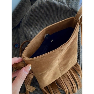 Detail view of the bohemian brown suede crossbody bag with fringe and magnetic closure
