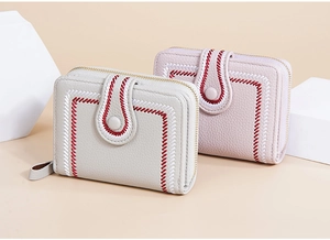 Close-up of embroidered PU leather short wallets in cream and pink with snap button closure