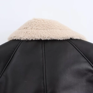 Close-up of black faux leather jacket featuring contrast beige faux fur collar detail