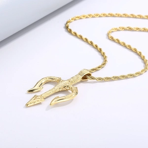 Gros plan d'un pendentif trident doré avec chaîne torsadée sur fond blanc propre