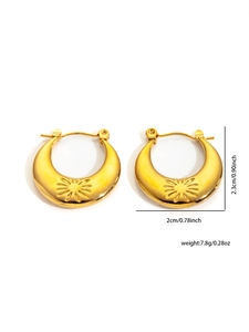 Detail view of golden crescent earrings with radial sunburst texture and size markings