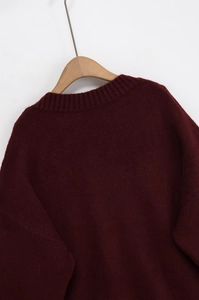 Detailed close-up of dark red knitted sweater texture on wooden hanger with soft fabric feel