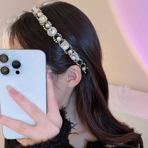 Close-up of elegant pearl and rhinestone headband with golden beads in mirror selfie