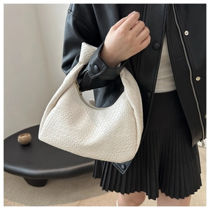 Modern white woven hobo bag with a knotted handle detail styled on a model outfit