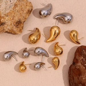 Detail of teardrop stud earrings in gold and silver finish with mirror polished surface