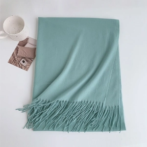 Macro detail of soft light blue cashmere-like scarf with fringe edges on white surface