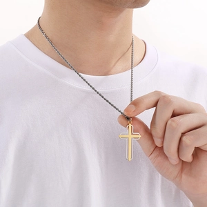 Close-up of a two-tone stainless steel cross necklace with a gold inlay and silver chain
