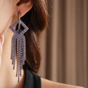 Detailed view of long purple rhinestone tassel earrings worn on a model for a formal look