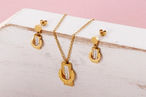 Detailed view of Roman numeral jewelry set with clear crystals on a pink background