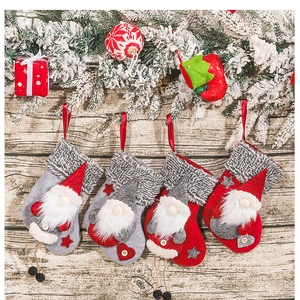 Detail of four festive Christmas stockings with gnomes on rustic snowy pine background