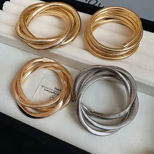 Set of four coiled snake bone bracelets in gold and silver finish with metallic texture