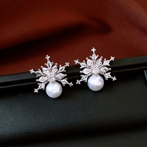 Macro detail of snowflake earrings with zircon crystals and a hanging white pearl