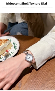 Close-up of elegant quartz watch with rhinestone bezel and seashell texture dial on wrist