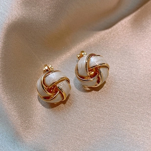 Gros plan de boucles d'oreilles nœud doré avec résine blanche sur soie champagne