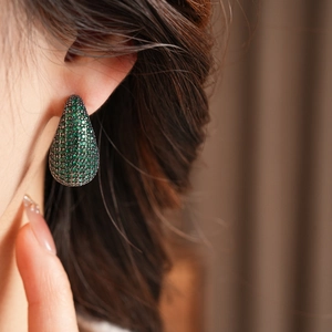 Gros plan détaillé de boucles d'oreilles vintage en forme de larme avec zircons verts