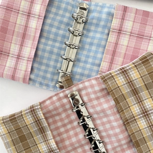 Close-up of fabric plaid binder covers in pink and brown with silver 6-hole metal ring